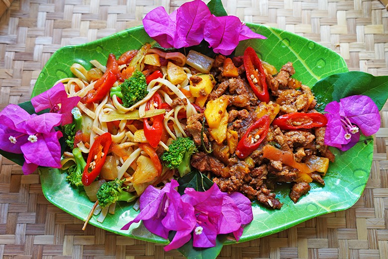 Gebratenes Schweinefleisch mit Ananas an bunten Nudeln