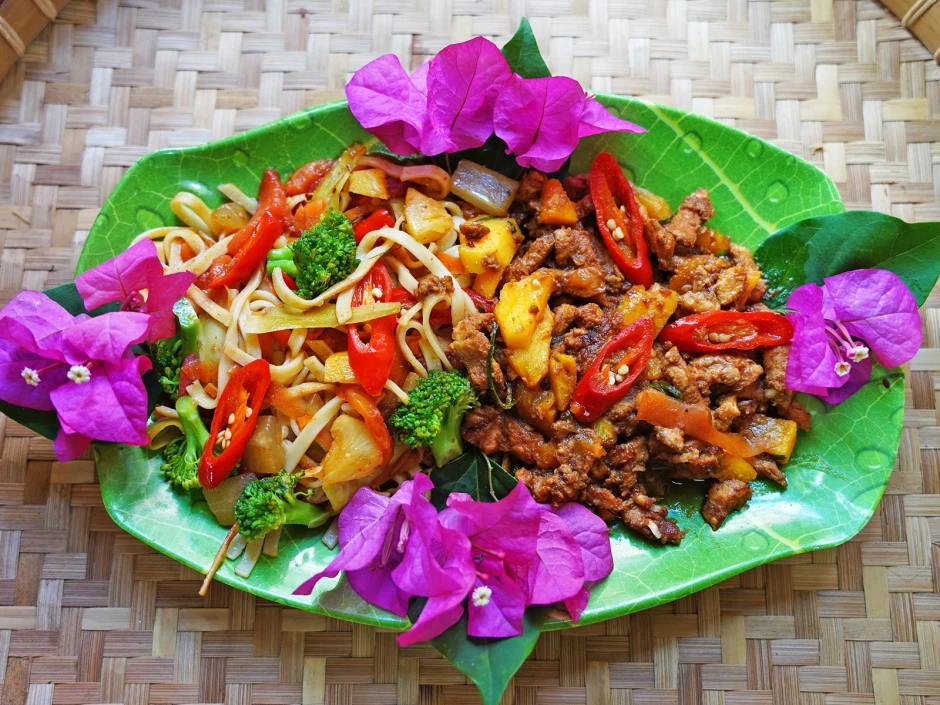 Gebratenes Schweinefleisch mit Ananas an bunten Nudeln