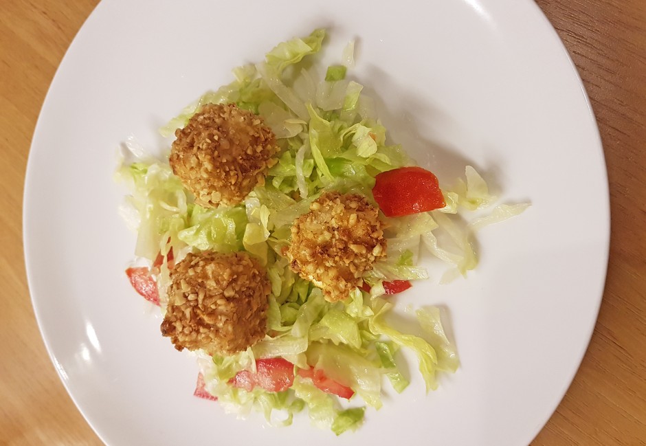 Schafkäsewürfel in Nusskruste auf Blattsalat