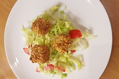 Schafkäsewürfel in Nusskruste auf Blattsalat