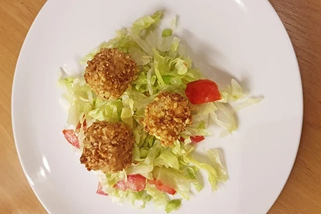 Schafkäsewürfel in Nusskruste auf Blattsalat